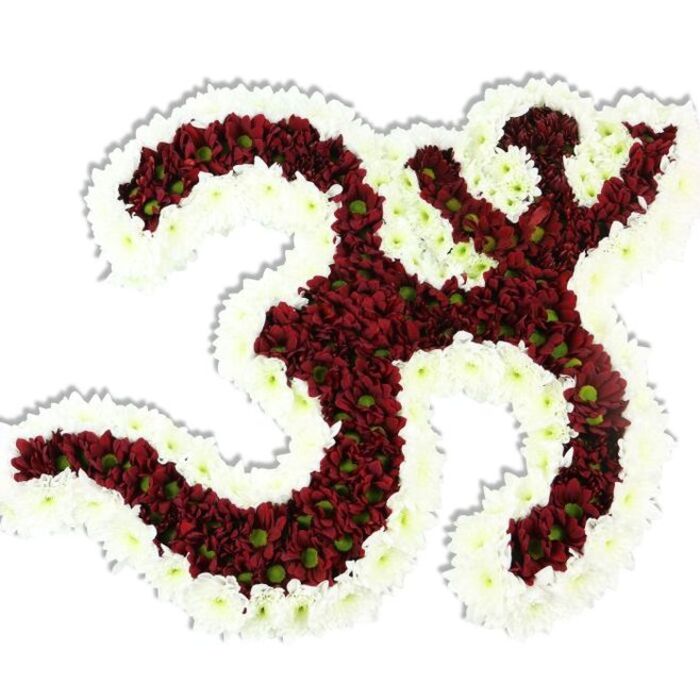 This intimate, hand-assembled floral depiction of the Om symbol balances devotion and botanical precision: the central body of the character is composed of densely arranged, small-headed chrysanthemums in a rich palette of maroon and deep red, their layered petals creating a plush, velvety mass punctuated by subtle lime-green centres. A substantial, flowing frame of immaculate white spray chrysanthemums outlines the symbol's distinctive '3'-like curve, downward stroke, and the crescent-and-dot above, the white rim both defining the negative spaces and giving the entire motif a luminous edge against the plain white background. The three-dimensionality is clear in the gentle drop shadow beneath the piece and in the way the petals catch a soft, diffuse light-suggesting cool morning delivery for a temple offering or a memorial table. The arrangement's scent is quietly earthy, the close-packed blooms hinting at late-summer gardens and a measured calm; its texture reads lush yet disciplined, the work of a florist attentive to rhythm and proportion. Imagined for occasions that range from spiritual gatherings and yoga workshops to respectful tribute services in Chigwell and nearby Roding Valley, the design honours tradition while remaining a piece of floral sculpture. As a local maker familiar with deliveries around Chigwell High Road and the green corridors toward Epping Forest, I see this as an elegant, contemplative emblem that holds both visual clarity and devotional warmth.